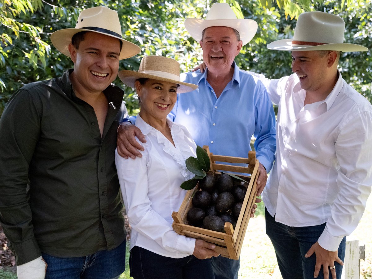 La familia en la huerta con un huacal de aguacates